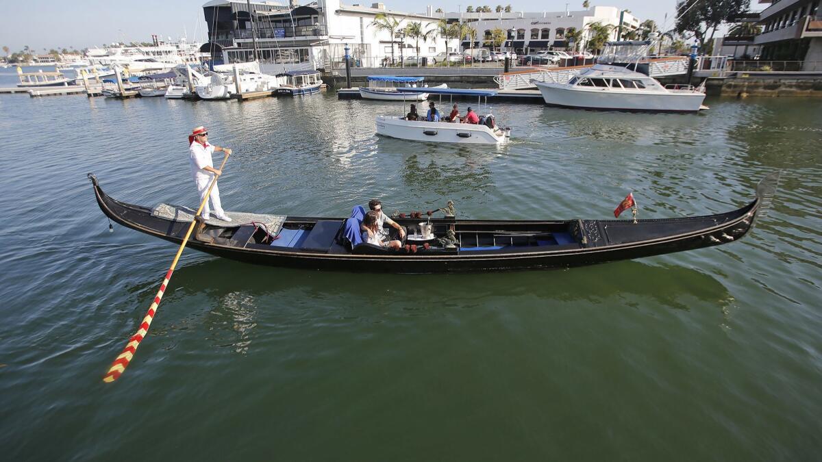 Gondola Adventures co-owner Greg Mohr paddles a couple up Newport Bay on one of his boats on Friday. The city’s last gondola operator will have to move in November and is looking for a location to continue their traditional Venetian-style canal cruises in Newport Harbor.