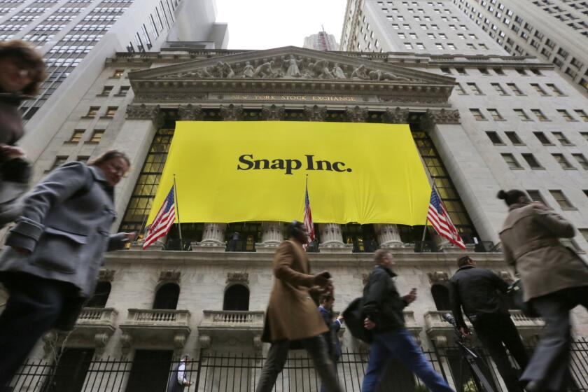 People pass by the New York Stock Exchange after the banner for the Snap Inc. IPO was raised on the building's facade, Wednesday, March 1, 2017. Snap Inc. is expected to start trading on the New York Stock Exchange on Thursday under the symbol "SNAP." (AP Photo/Richard Drew)