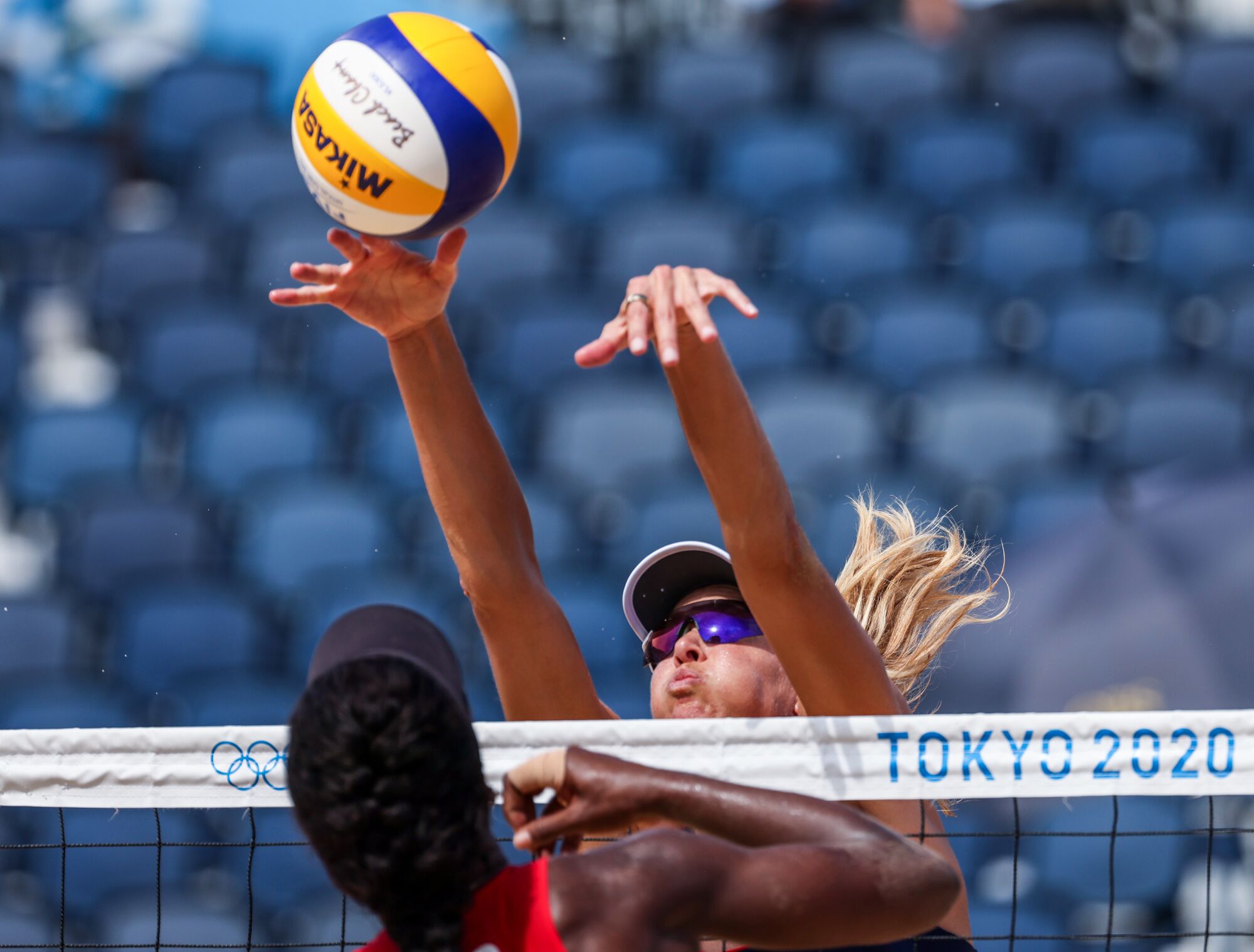 Two women at the net with the volleyball above.