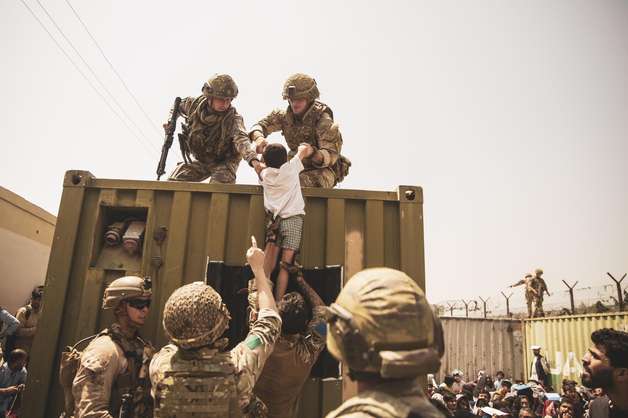 British and Turkish coalition forces, along with U.S. Marines, assist a child during an evacuation 