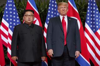 North Korean President Kim Jong Un stands in front of flags with former U.S. President Donald Trump