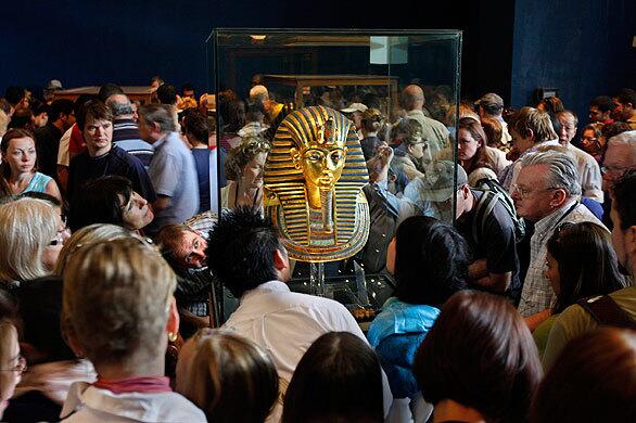 Visitors to the Egyptian Museum in Cairo crowd around the golden mask of Egypt's famous King Tutankhamen. He likely died of complications from a broken leg exacerbated by malaria, according to the new research on the mummy.