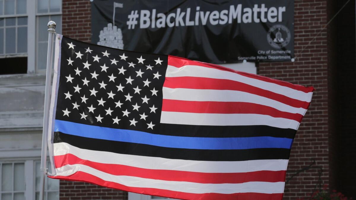A flag with blue and black stripes in support of law enforcement officers flies at a protest by police and their supporters outside City Hall in Somerville, Mass., in 2016.