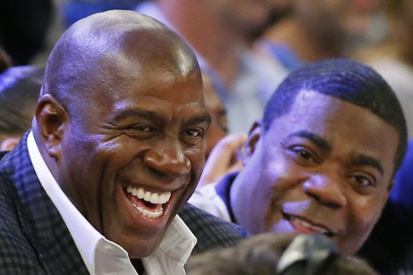 Magic Johnson and comedian Tracy Morgan sit on the sidelines during a game between the Los Angeles Lakers and the New York Knicks at Madison Square Garden on Nov. 8. Johnson is joining the effort to bring the Summer Olympics back to Southern California.