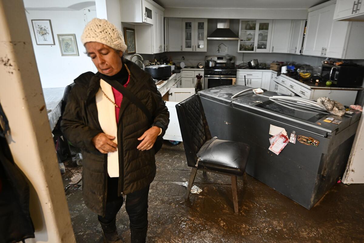 A woman looks over her flood-damaged home 