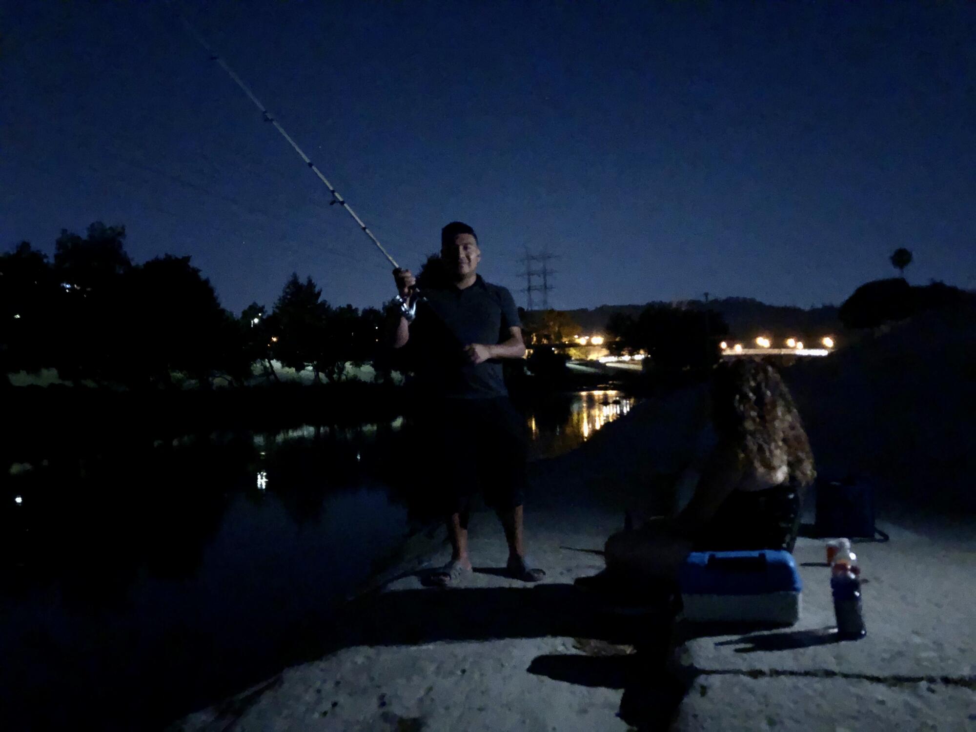 Alex Mendoza fishes with a friend after sunset.