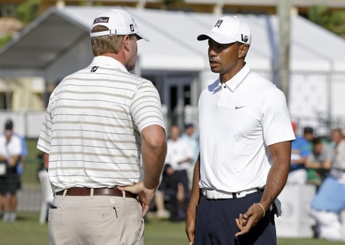 Steve Stricker, left, gives some advice to Tiger Woods on the practice putting green.