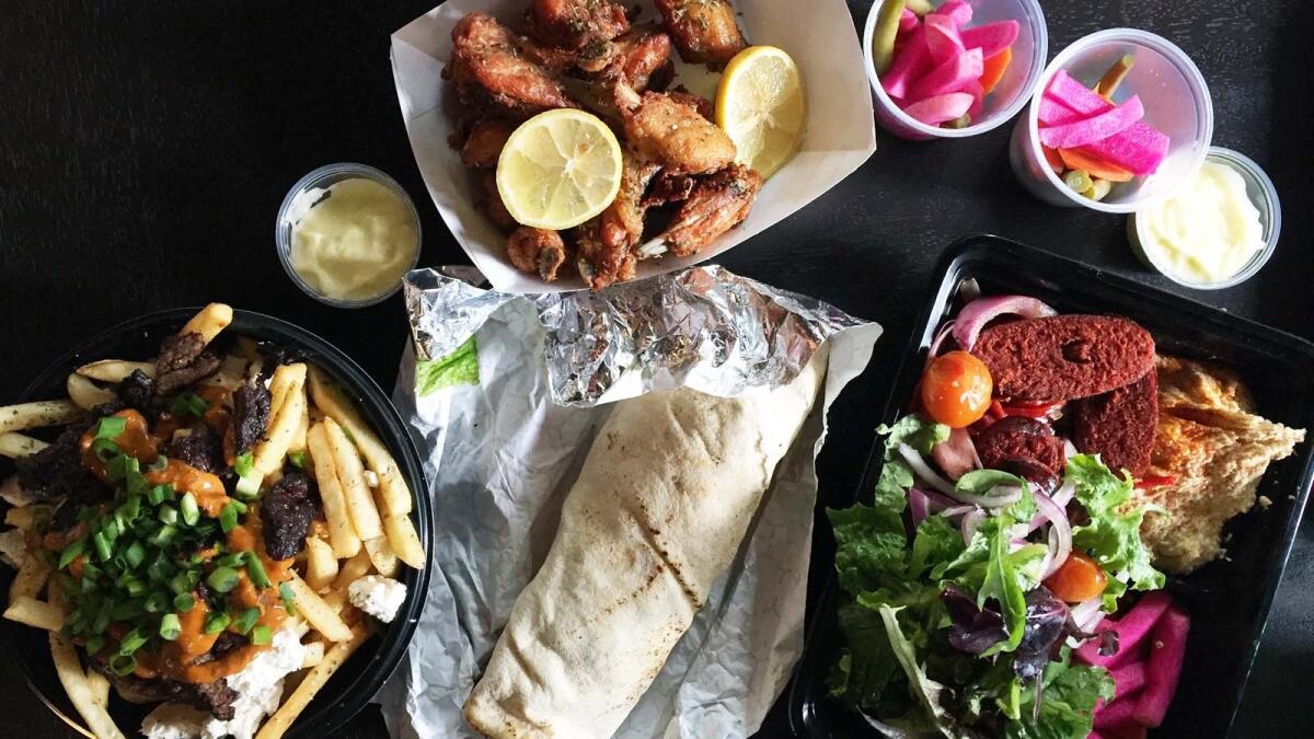 A variety of dishes from Souk Shawarma in downtown Los Angeles, including "dirty" fries, a beef shawarma wrap, chicken wings and soujouk sausage shawarma.