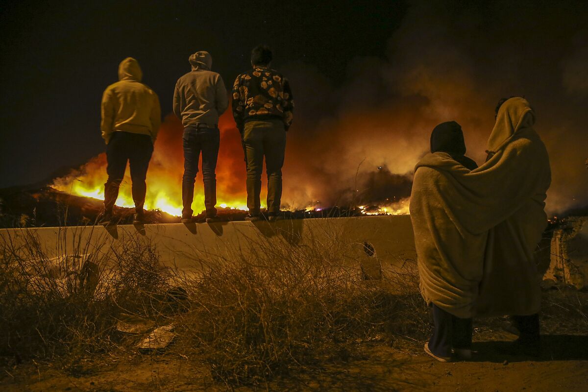 Oxnard residents view the Maria Fire from a cul-de-sac near Highway 126 as it slowly burns through the night near the Santa Clara River in Santa Paula.