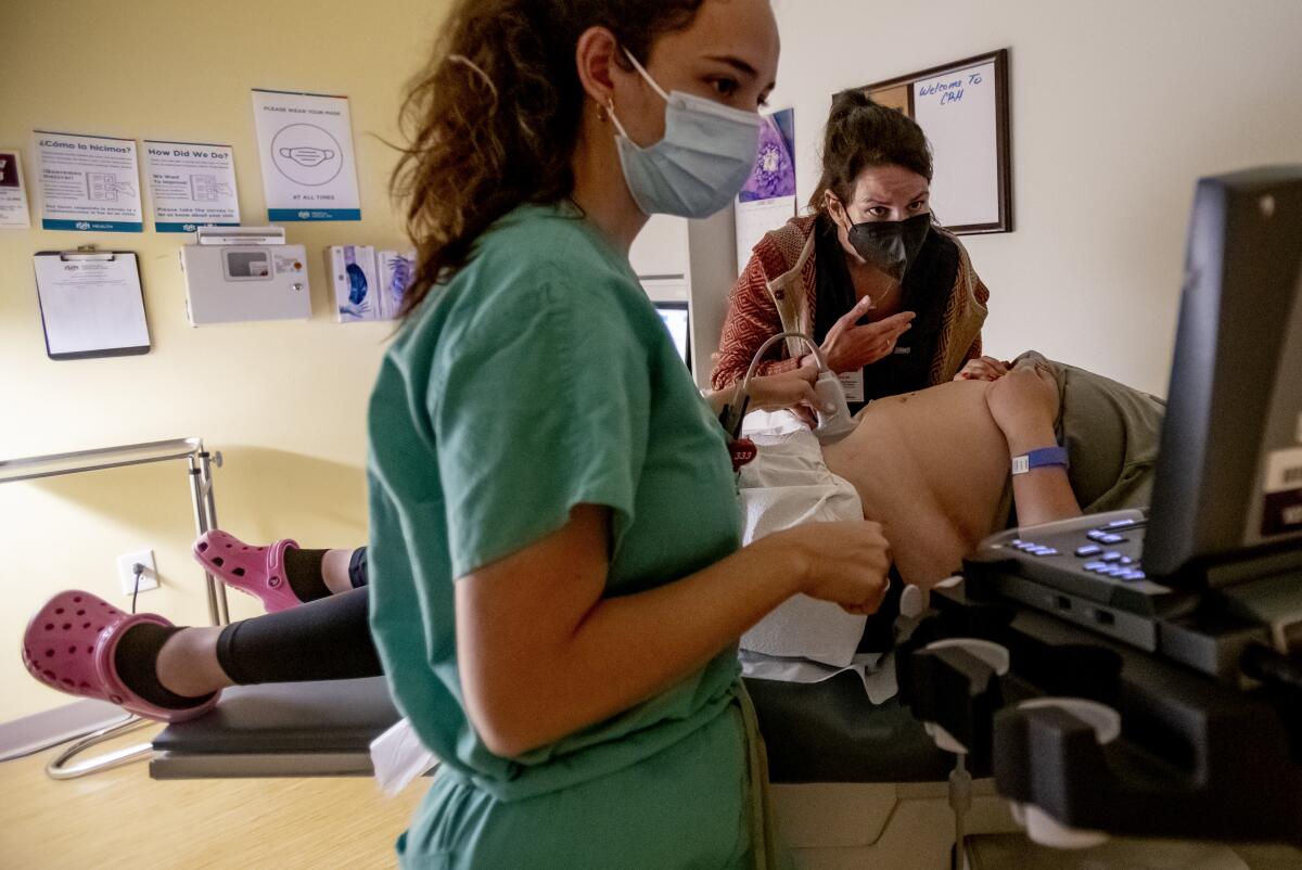 A physician and her resident perform an ultrasound on a patient 