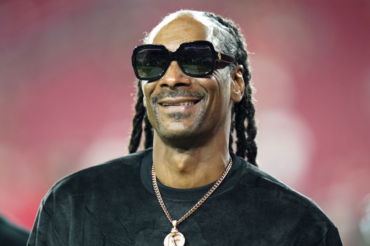 FILE - Entertainer Snoop Dogg walks on the field before an NFL football game between the Tampa Bay Buccaneers and the New Orleans Saints Sunday, Dec. 19, 2021, in Tampa, Fla. Snoop Dogg says he won’t let the big Super Bowl stage rattle his nerves. The ultra-smooth rapper said he will worry about his upcoming halftime performance after the fact. He’ll take the stage with Dr. Dre, Eminem, Kendrick Lamar and Mary J. Blige during Super Bowl 56 on Sunday, Feb. 13, 2022. (AP Photo/Chris O'Meara, File)