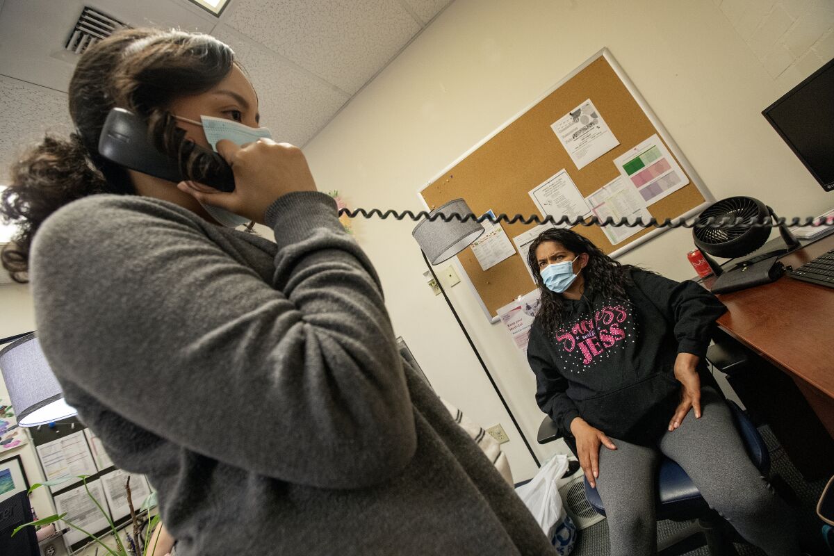 Valerie Ibarra-Figueroa, left, a health insurance specialist at the Venice Family Clinic, talks on the phone to