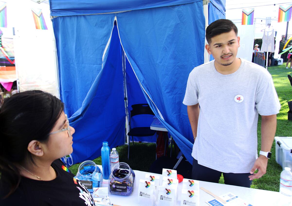 Miguel Barragan from Radiant Health Centers, right, answers questions about the on-site free HIV testing booth on Saturday.