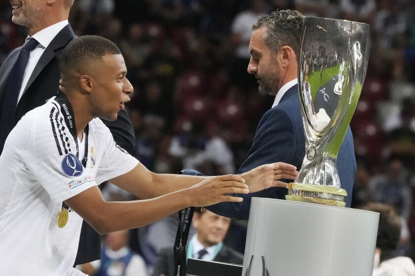 Real Madrid's Kylian Mbappe touches the trophy during the medal ceremony for the UEFA Super Cup Final soccer match between Real Madrid and Atalanta at the Narodowy stadium in Warsaw, Poland, Wednesday, Aug. 14, 2024. (AP Photo/Czarek Sokolowski)