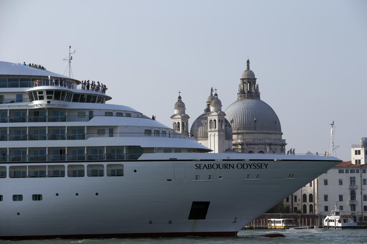 A large cruise ship with the name Seabourn Odyssey in front of domed Italian buildings in Venice