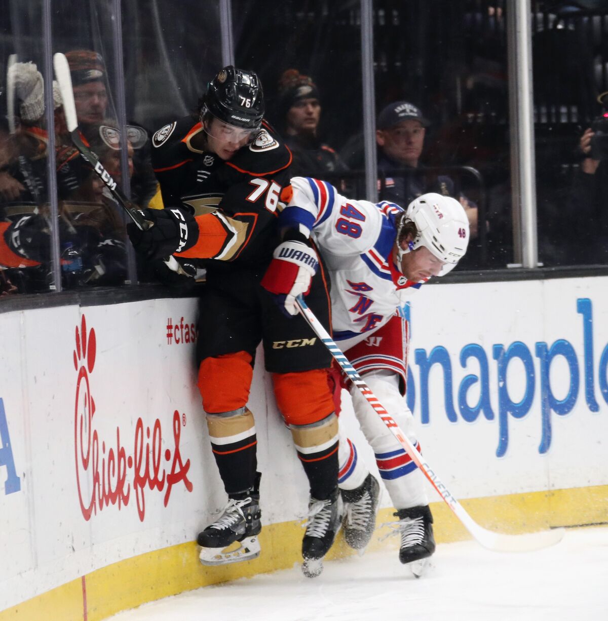 Ducks' Josh Mahura (76) is checked by New York Rangers' Brendan Lemieux (48) during the second period at the Honda Center on Saturday.