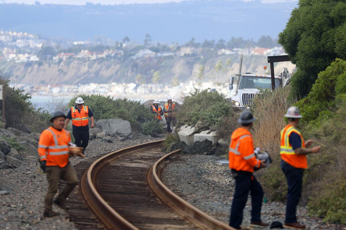 Workers clear the railroad tracks after a landslide in San Clemente 