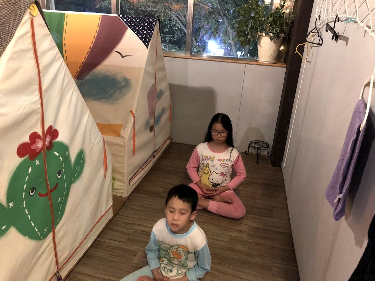 Yu Chung-chieh, 7, foreground, and Yu Shan-chen, 12, say prayers before bedtime at Ponponwu, an indoor campground in Taiwan. 