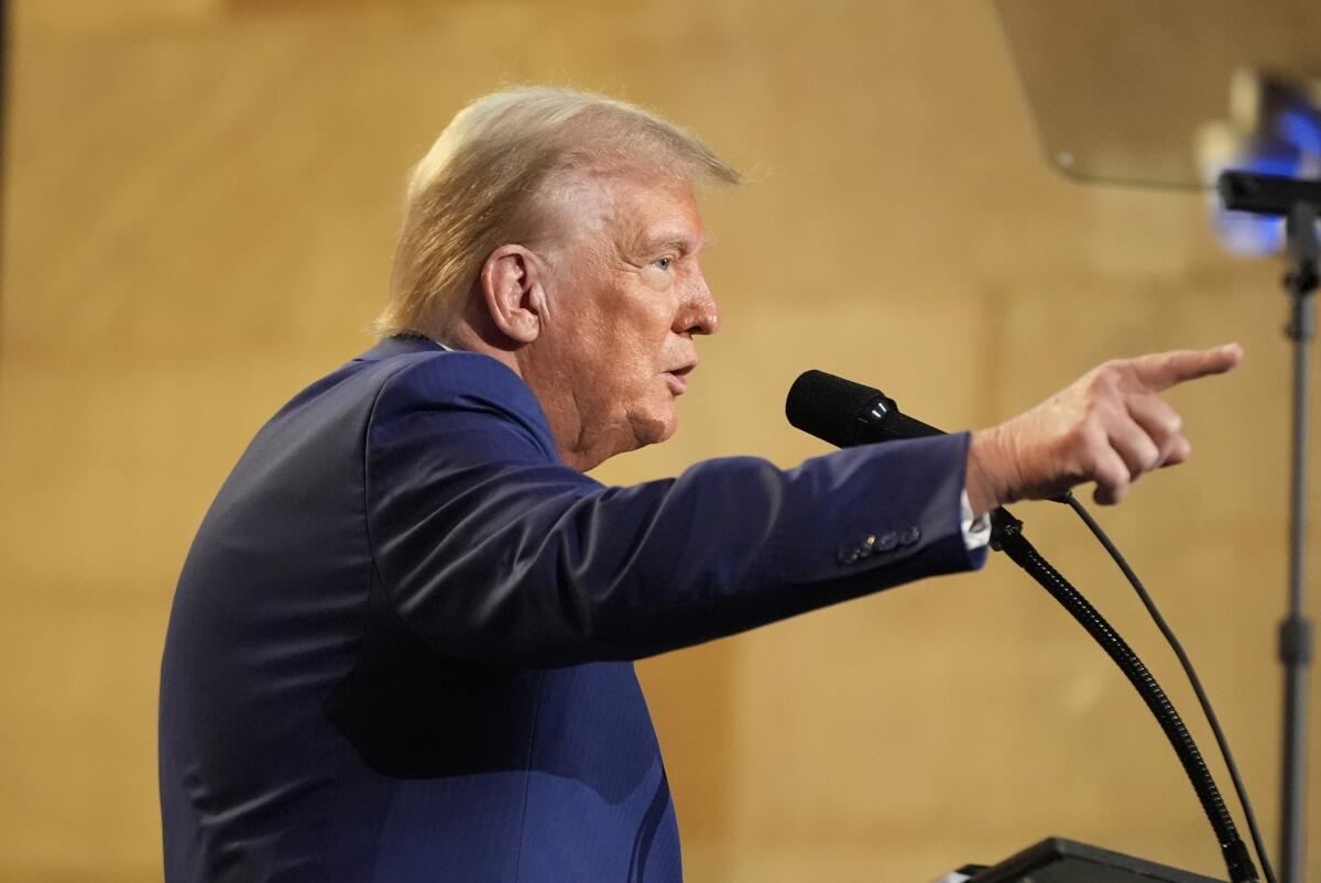 Former President Trump points while speaking at a microphone