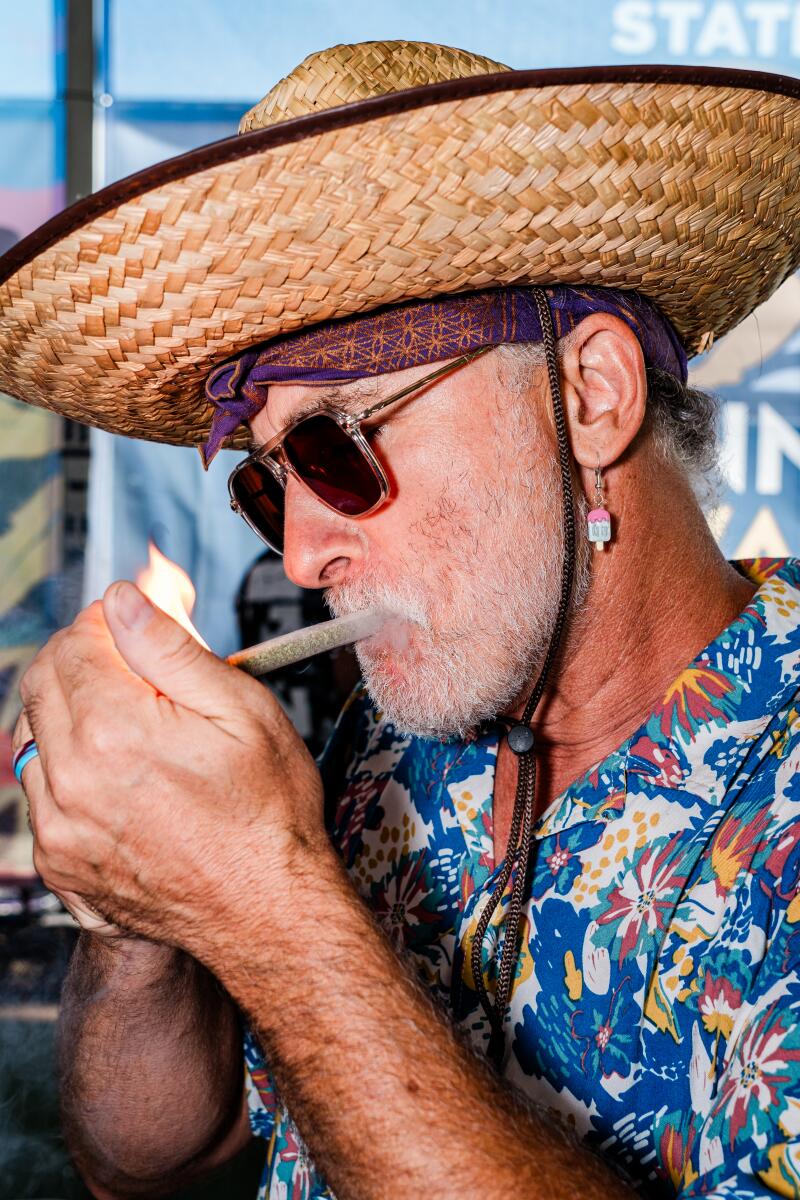 A man in a straw hat lights a joint
