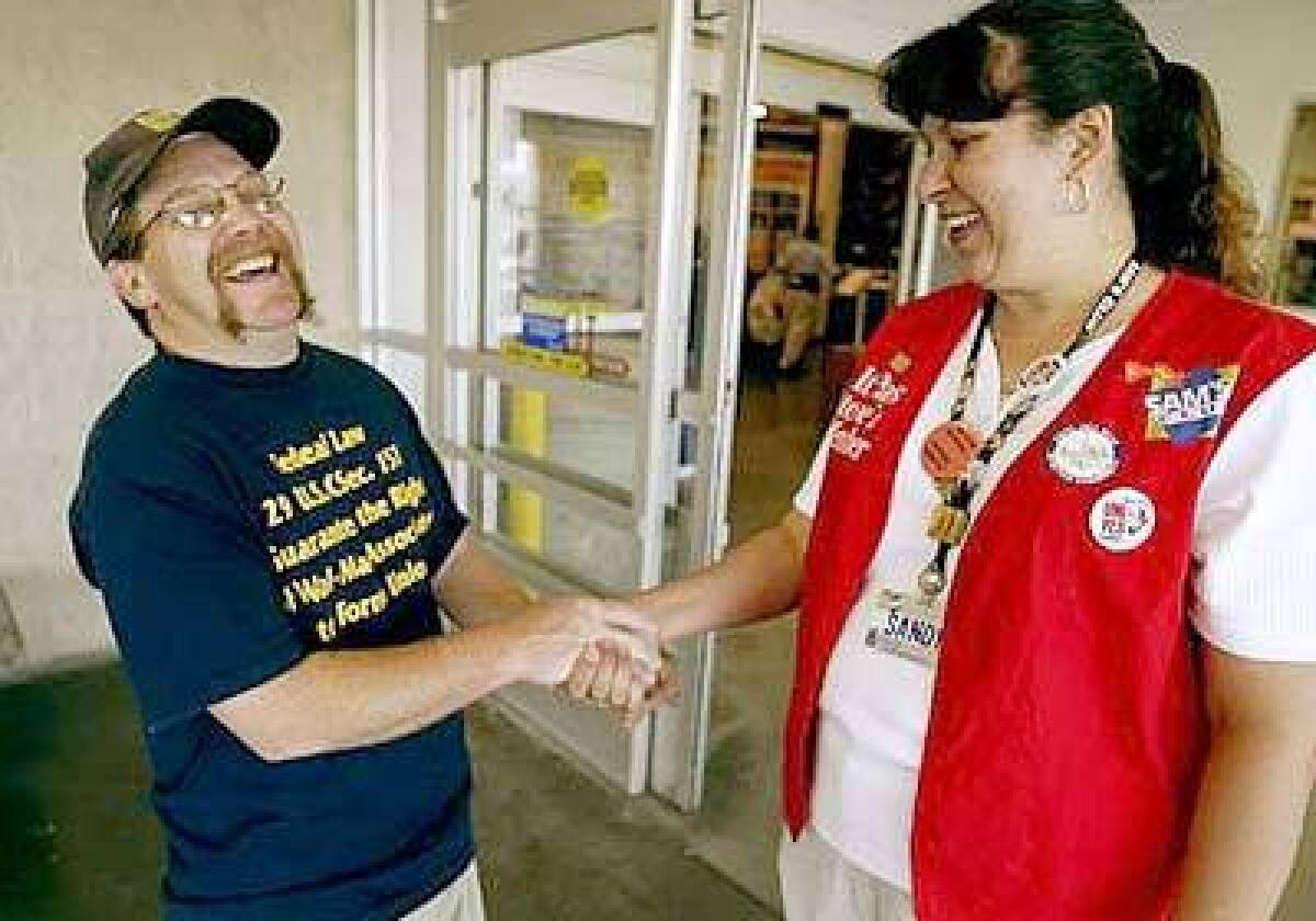 Wal-Mart employee Larry Allen, left, shakes hands with Sam's Club employee Sandy Williams at a Sam's Club in Las Vegas. Each is trying to unionize their stores.
