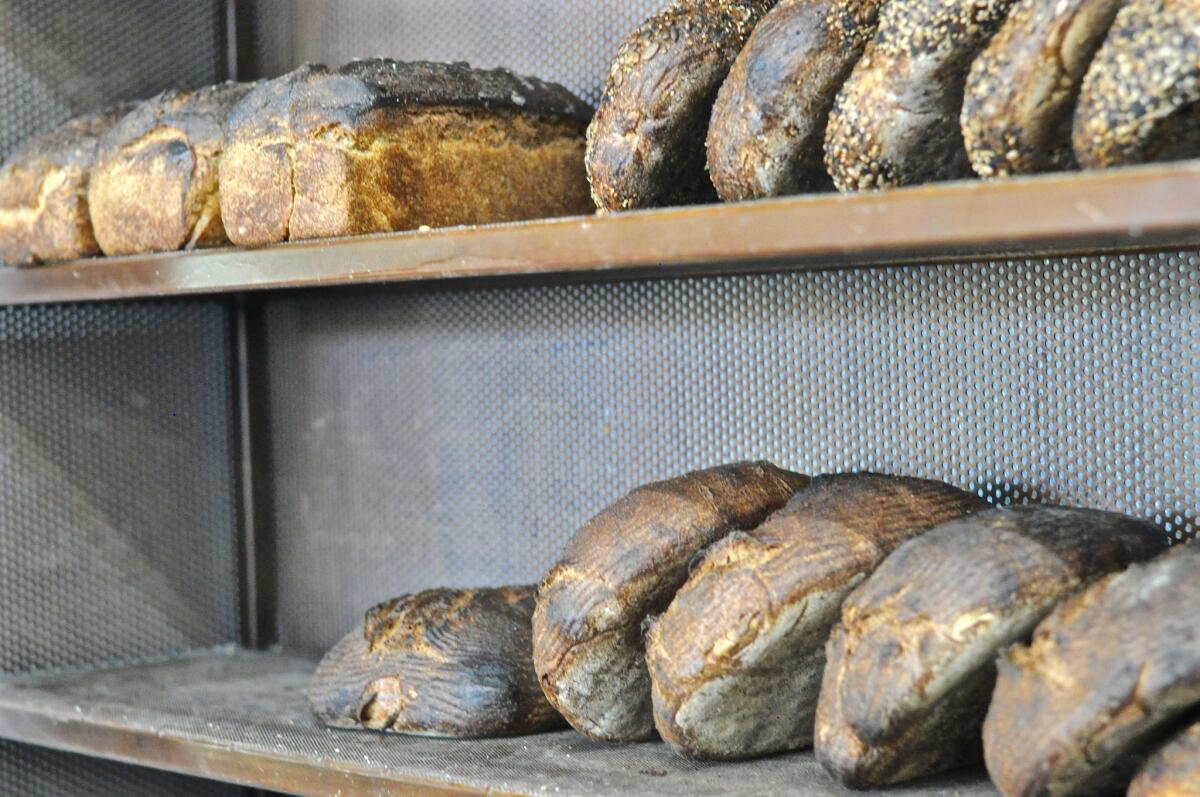 Loaves of spelt, whole wheat and seeded bread sit on the shelves beside the deck oven at Lodge Bread in Culver City.