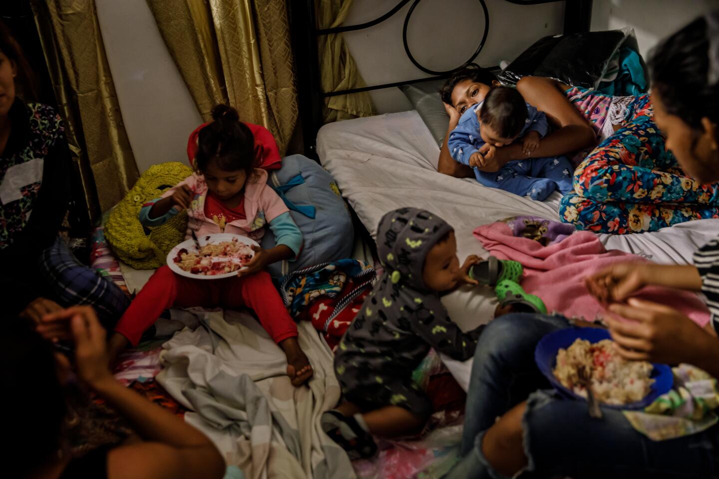 Nevrimar Barreto, top right, holds son Yhoimer Alvarez, 1, as they take refuge in a room set aside for Venezuelan mothers at Martha Duque’s home turned migrant shelter.