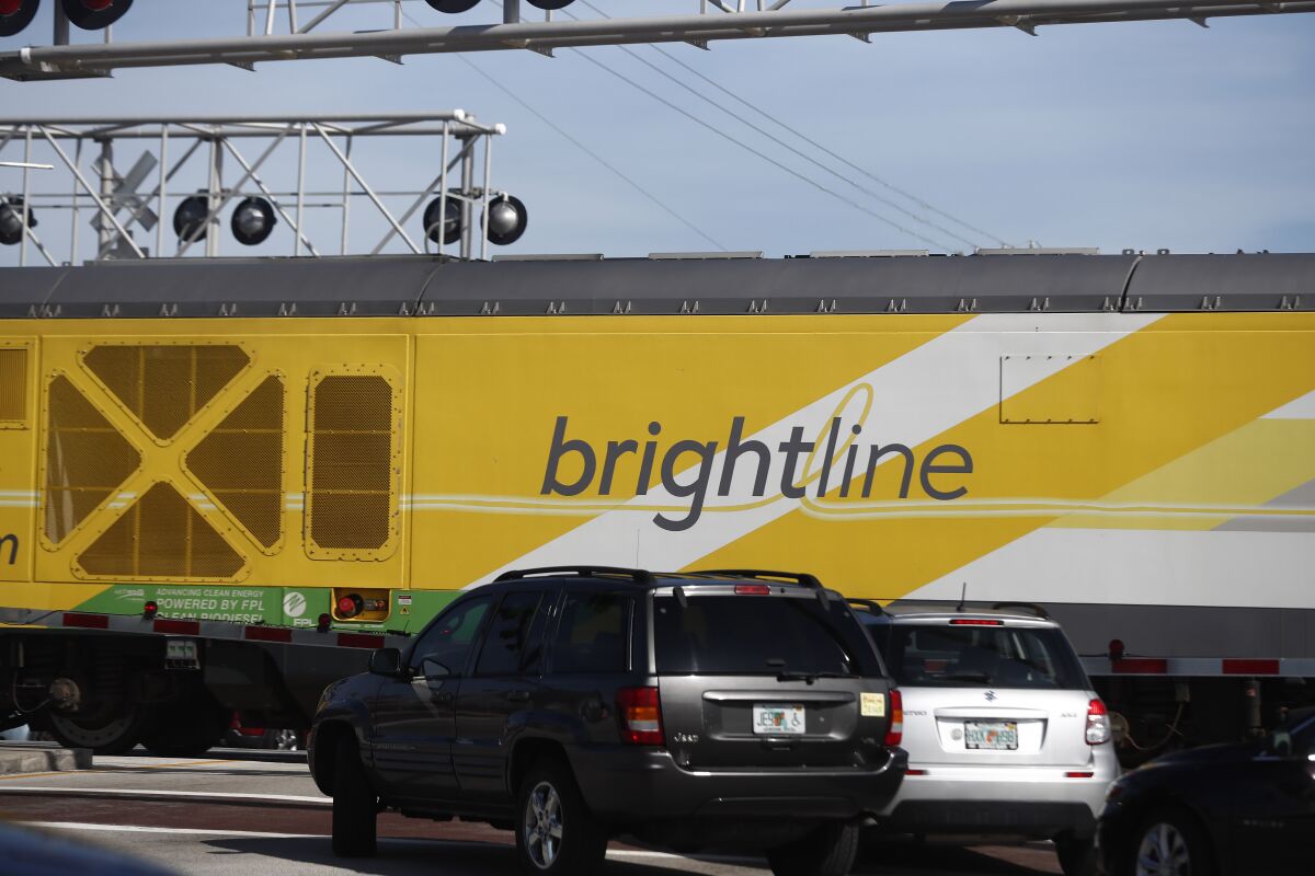 FILE - Vehicles wait for a Brightline passenger train to pass, Nov. 27, 2019, in Oakland Park, Fla. A train belonging to Florida’s higher-speed passenger rail service struck and killed a man walking on the tracks just weeks after the company reopened from the pandemic. The Brightline train struck the pedestrian Tuesday morning in North Miami Beach as he walked on the tracks and didn’t move as the train sounded its horn. North Miami Beach police did not immediately return a call Wednesday, Dec. 8, 2021 seeking further details. (AP Photo/Brynn Anderson, file)