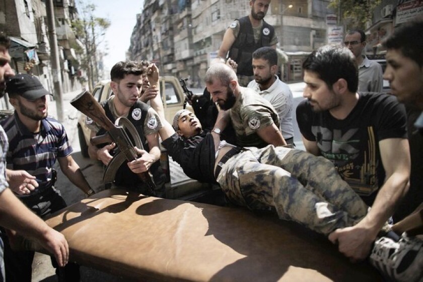 Rebels help a comrade wounded in a Syrian army strike in the northern city of Aleppo on Tuesday.
