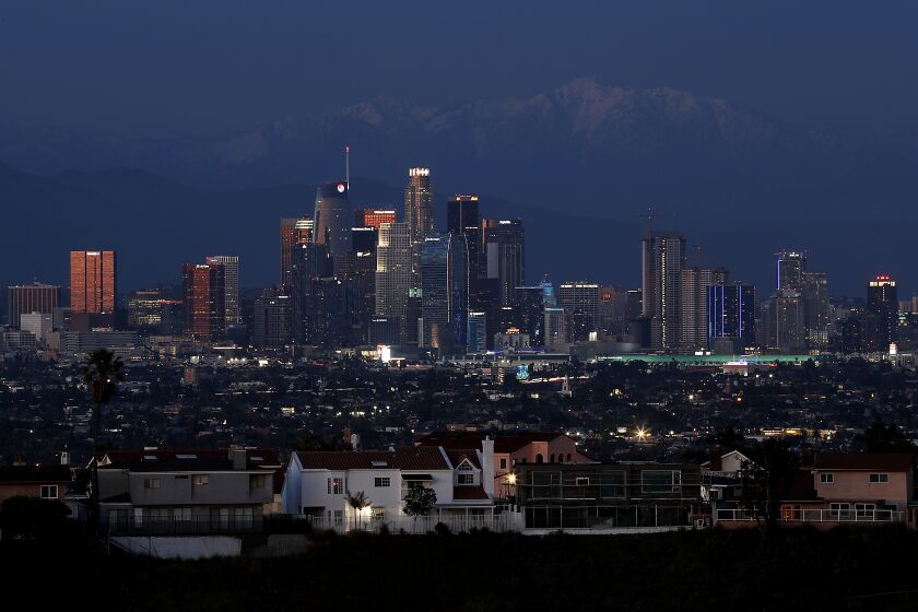 LOS ANGELES, CALIF. - APR. 15, 2020. Dusk settles on downtown Los Angeles and the snow-capped peaks og Mount Baldy as Southern California completes a month of coronavirus lockdown. (Luis Sinco/Los Angeles Times)