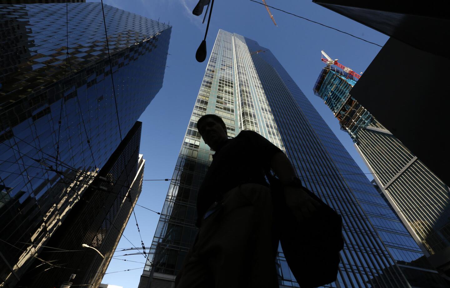 A pedestrian walks past the luxury Millennium Tower, a 58-story high rise in San Francisco.