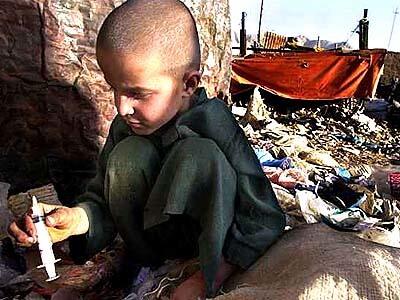 7-yr-old Issa finds a syringe while sorting garbage at a recycle depot in Quetta, Pakistan.