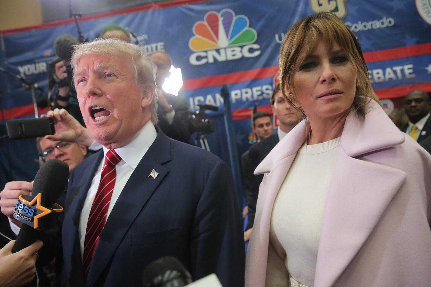 Melania Trump (R), wife of presidential candidate Donald Trump, listens to her husband speak to the media in the spin room after the CNBC Republican Presidential Debate at University of Colorado's Coors Events Center in Boulder, Colo.