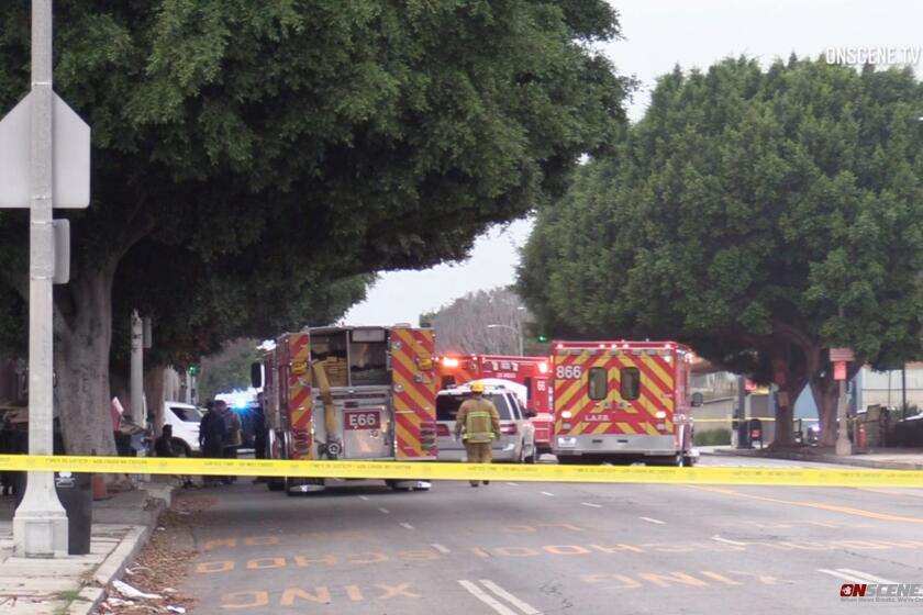 Firetrucks and ambulances around an SUV on a street behind crime scene tape