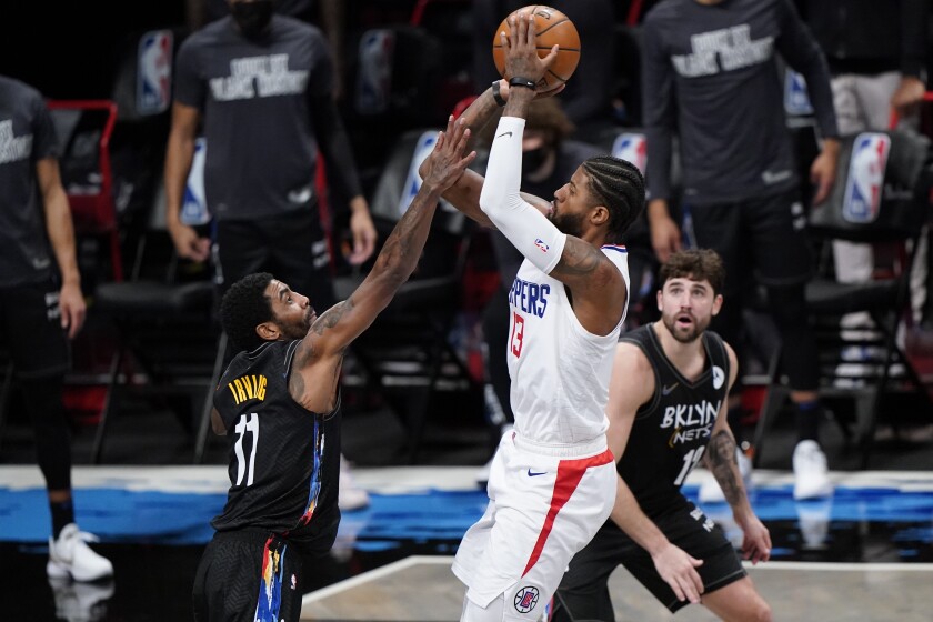 Brooklyn Nets guard Kyrie Irving defends against Clippers guard Paul George as Nets forward Joe Harris watches.