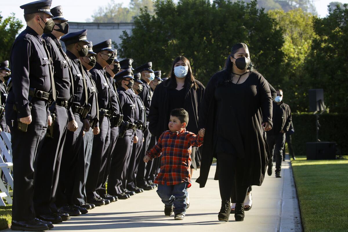 Janet Covarrubias walks past LAPD officers with her 2-year-old son, Alexander Covarrubias.