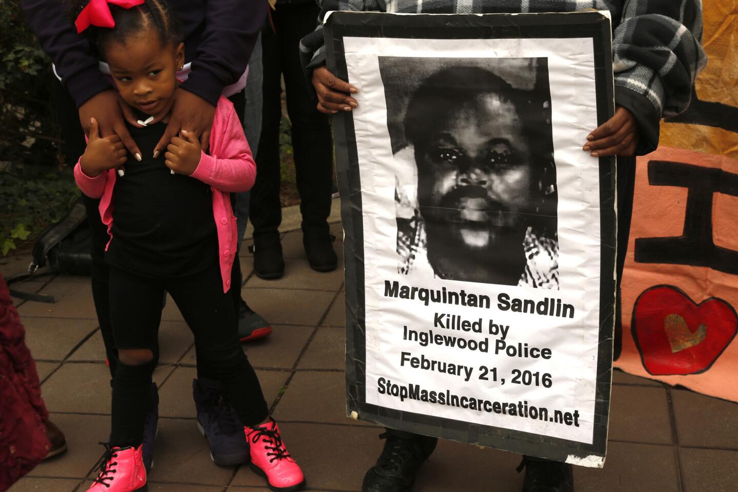 Kylia Fields, 3, stands next to a poster of her cousin as family and community members rally to demand more information in the deaths of Kisha Michael and Marquintan Sandlin in front of City Hall in Inglewood on Feb. 21. Inglewood police officers shot and killed the couple a year ago to the day.