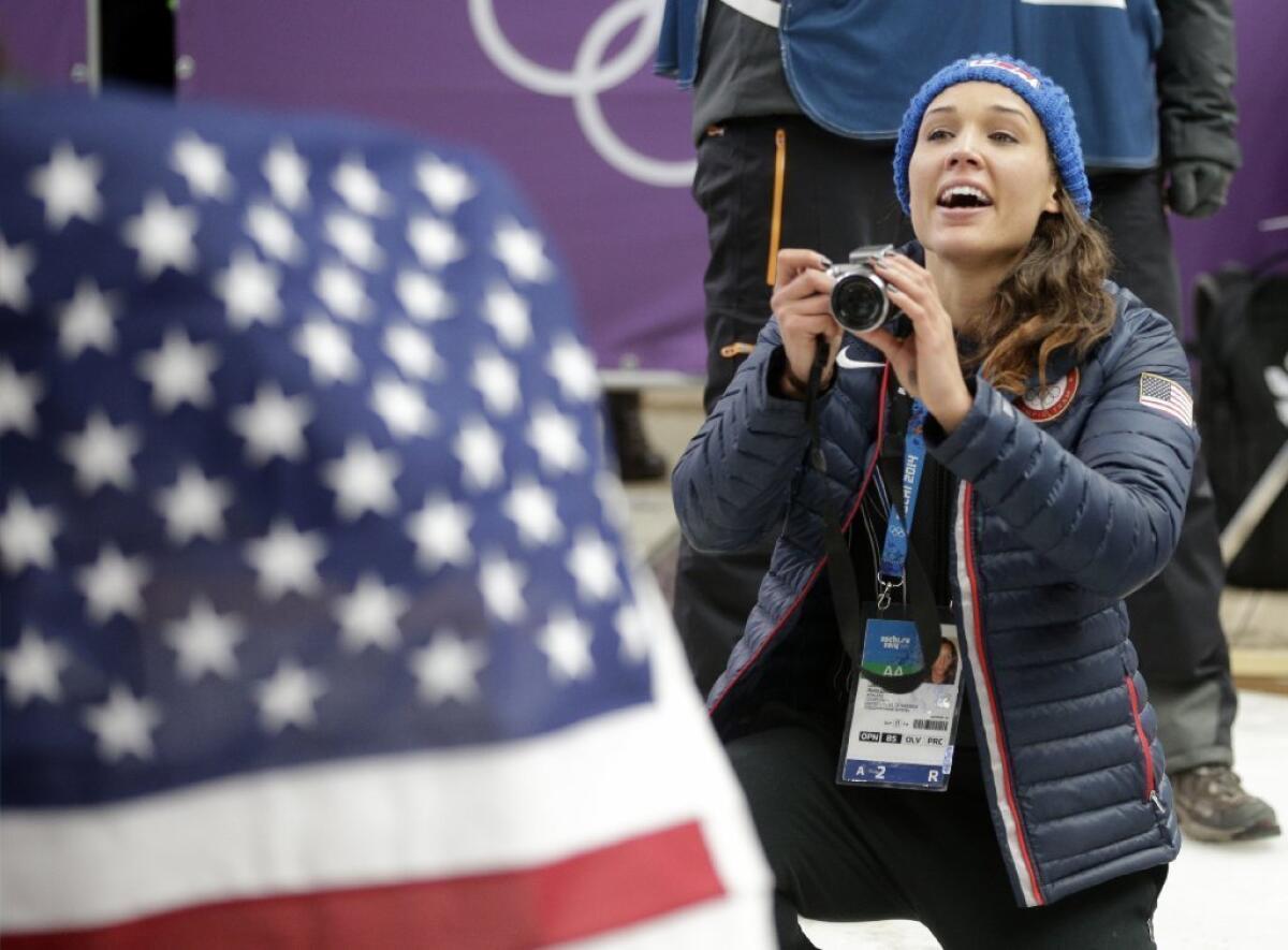 American bobsledder Lolo Jones takes pictures of her teammates after they won silver and bronze during the women's bobsled competition at the 2014 Olympics on Feb. 19.