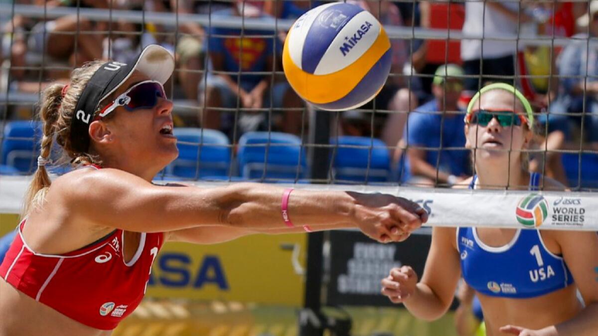 April Ross passes to teammate Kerri Walsh Jennings while opponent Summer Ross waits and watches during a round-of-16 match at the Long Beach Grand Slam.