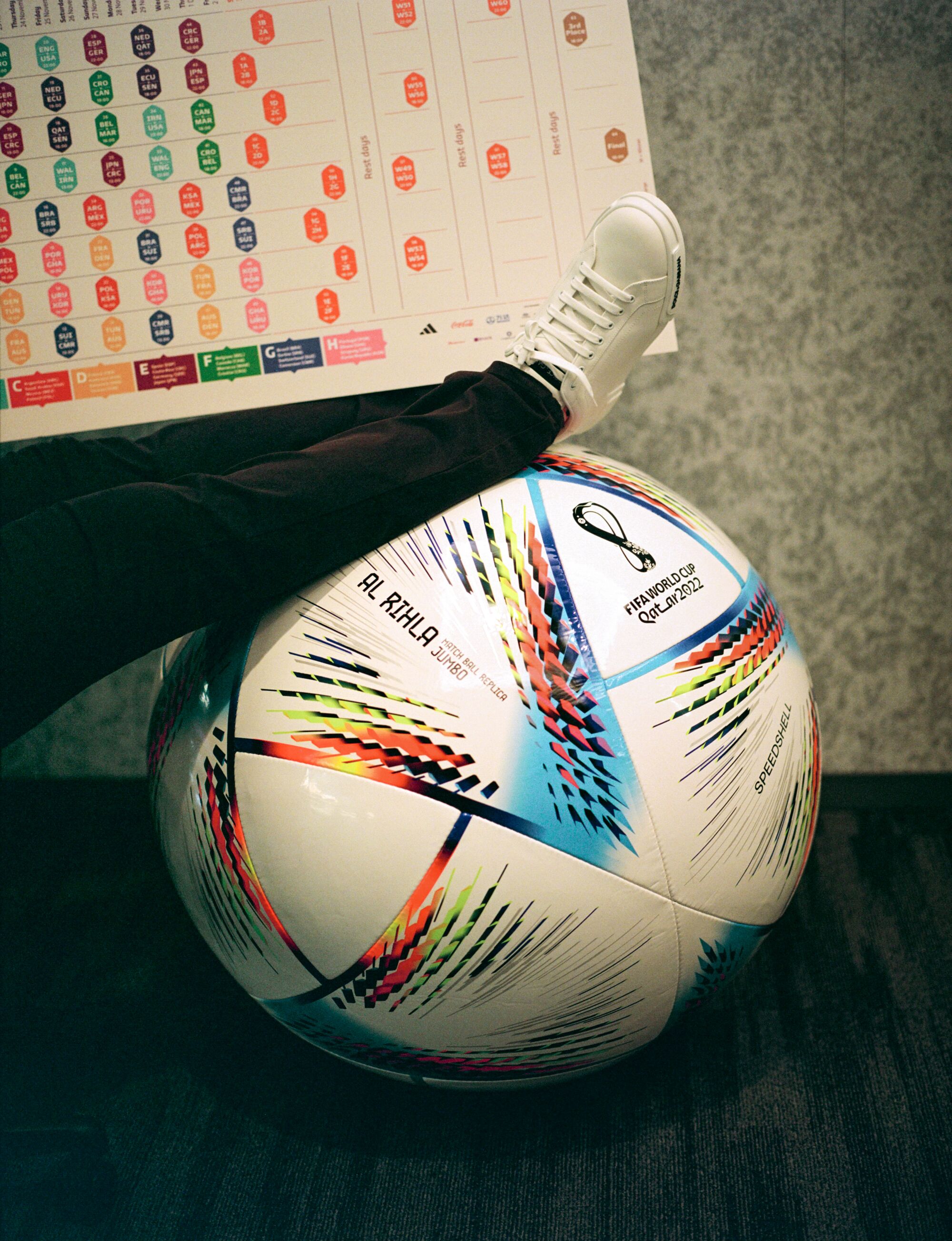 A man rests a leg on a FIFA World Cup soccer ball.