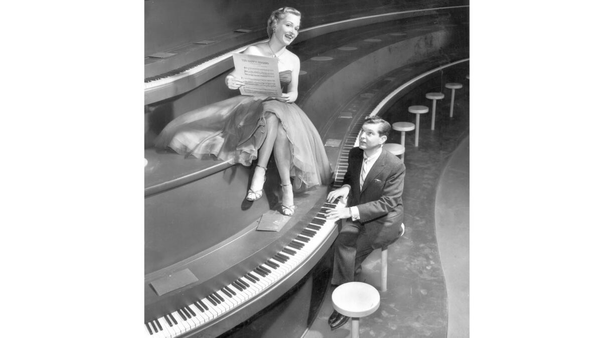 Mary Healy and Peter Lind Hayes at a huge piano in "The 5,000 Fingers of Dr. T," a musical fantasy based on a story by Theodor Seuss Geisel about a boy who hates practicing piano. This photo was published in the March 23, 1952, L.A. Times.