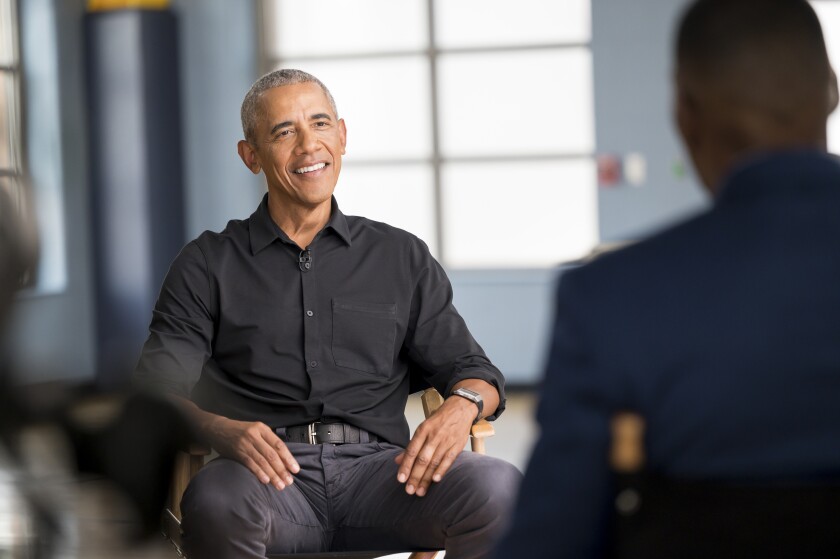 Michael Strahan, right, sits across from former President Barack Obama during an interview