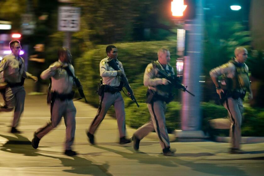 FILE - In this Oct. 1, 2017, file photo, police run for cover at the scene of a shooting near the Mandalay Bay resort and casino on the Las Vegas Strip in Las Vegas. A judge in Las Vegas on Wednesday, Feb. 7, 2018, has ordered police to release 911 calls, body camera video and several other records that the department had sought to keep from the public until it concluded the investigation into last year's mass shooting (AP Photo/John Locher, file)