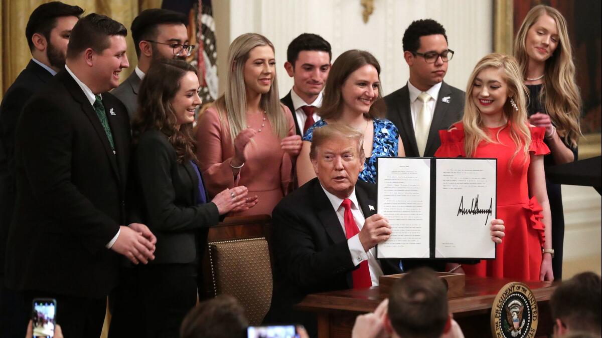 President Donald Trump holds up an executive order he signed protecting freedom of speech on college campuses during a ceremony in the East Room at the White House on March 21.