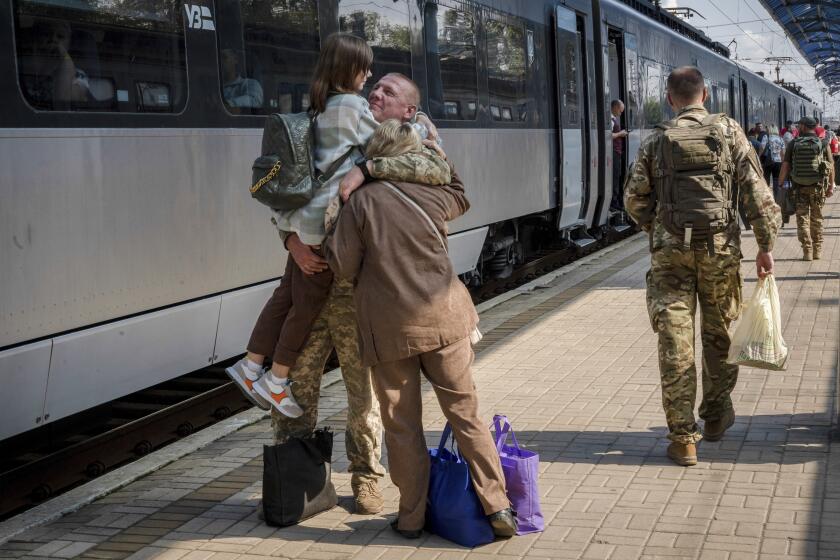 A Ukrainian serviceman hugs his wife and the daughter at the railway station in Sloviansk, Donetsk region, Ukraine on Tuesday, Sept. 12, 2023. The train that runs from Ukraine's capital, Kyiv, to the city of Kramatorsk in the east stands apart from others in Ukraine. It is shrouded in solemn silence as passengers anticipate their final destination — in front-line areas where battles rage between Ukrainian and Russian forces. (AP Photo/Hanna Arhirova)