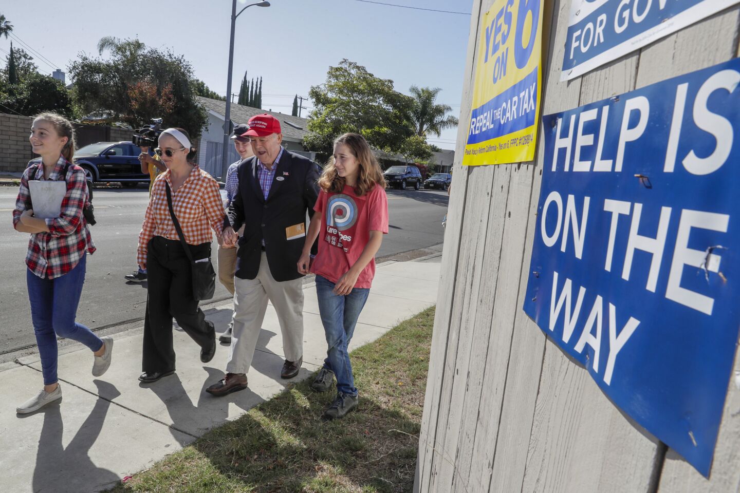 Rep. Dana Rohrabacher is escorted by his family, wife Rhonda daughters Annika, left, Tristen, right and son, Christiran, back, as he drops off a mail-in ballot to the Boys and Girls Club of Costa Mesa.
