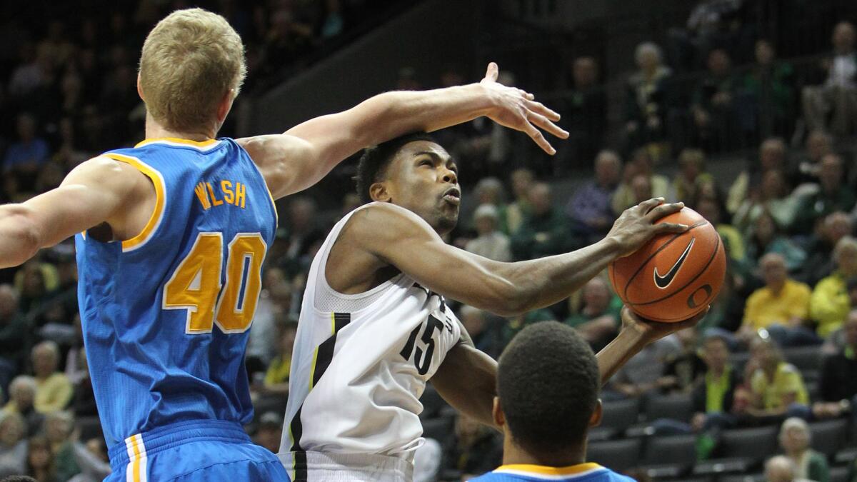 Oregon's Jalil Abdul-Bassit, center, drives to the basket between UCLA's Thomas Welsh, left, and Norman Powell during the first half of the Bruins' 82-64 loss Saturday.