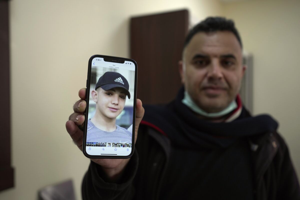 FILE - Muamar Nakhleh, father of Amal Nakhleh, a Palestinian teen with a rare neuromuscular disorder, who has been held without charge for a year in what Israel refers to as "administrative detention," shows his photo at his office, in the West Bank city of Ramallah, Jan, 10, 2022. Israel has extended the detention of Amal Nakhleh who turned 18 this week. On Tuesday, Jan. 18, 2022, his father confirmed that his detention has been extended until mid-May. (AP Photo/Majdi Mohammed, File)