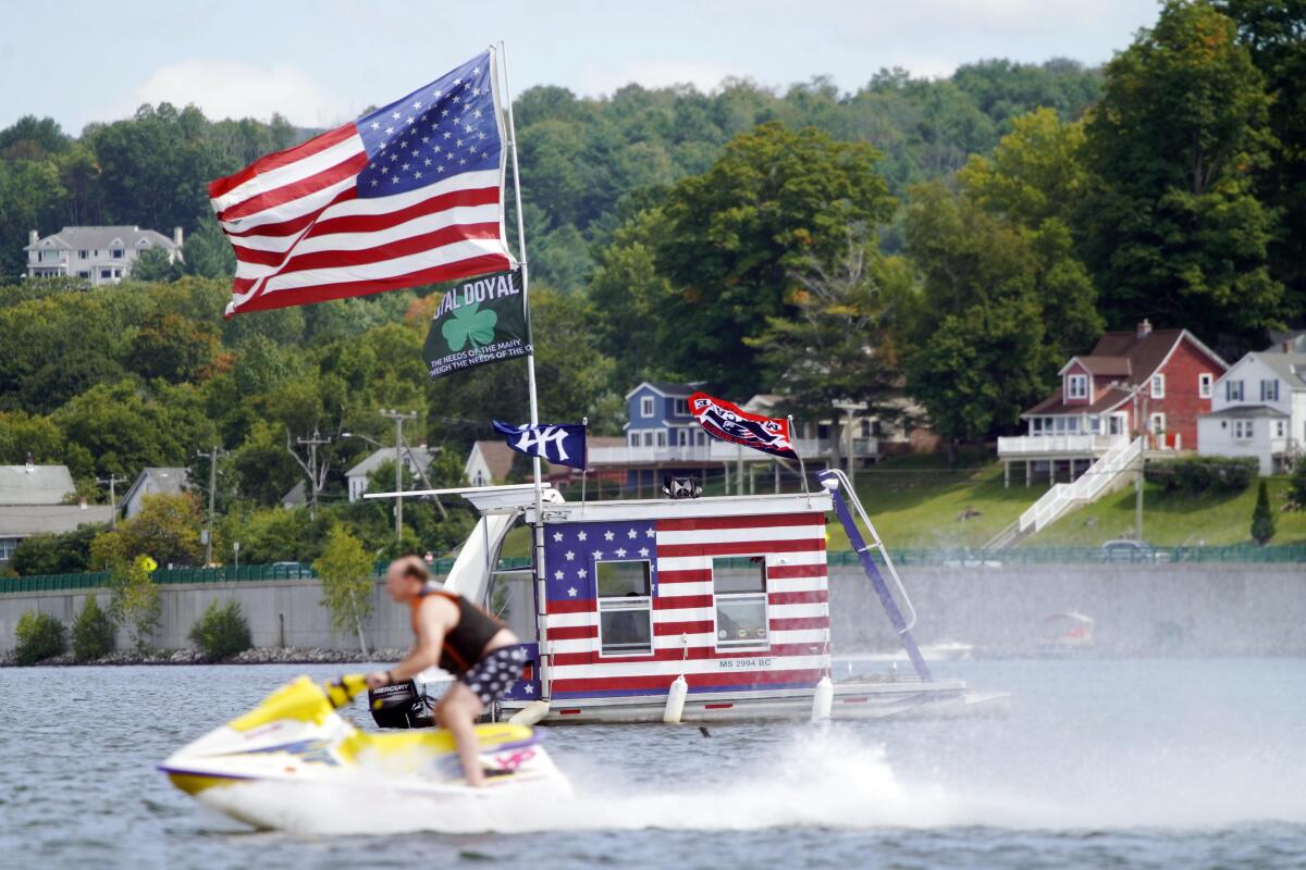 A jet skier passes a patriotic boat owned by AJ Crea on Pontoosuc Lake on Labor Day in Pittsfield, Mass., on Monday.