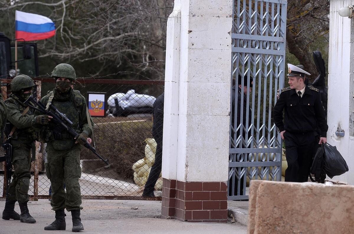 A Ukrainian officer, right, leaves a base in the Crimean city of Novoozerne after it was taken by Russian forces.